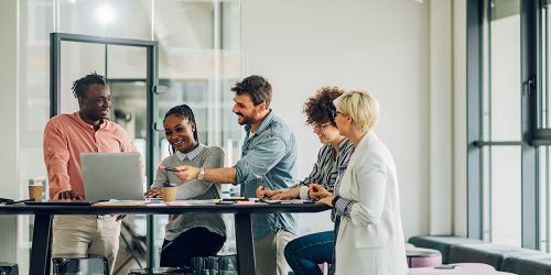 Diverse employees gathered in the office having fun during brainstorming while discussing new ideas for their new project. Multiracial coworkers gather in boardroom discuss ideas in group at briefing.